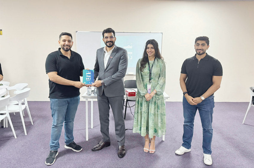 Ahmed Helal from The Socks Store receiving the Exporters – Youth Championship award, standing with event organizers and fellow participants during the ceremony in Bahrain.