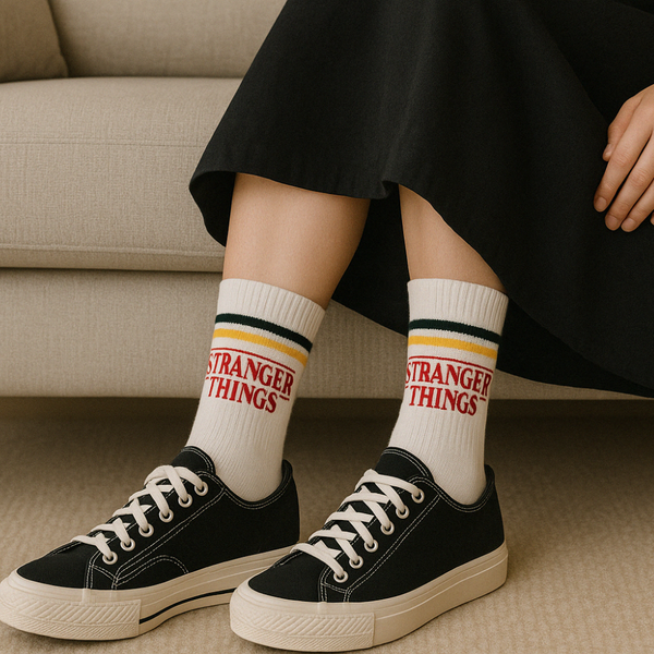 Model wearing white crew socks with black and yellow stripes and red 'Stranger Things' logo styled with black sneakers